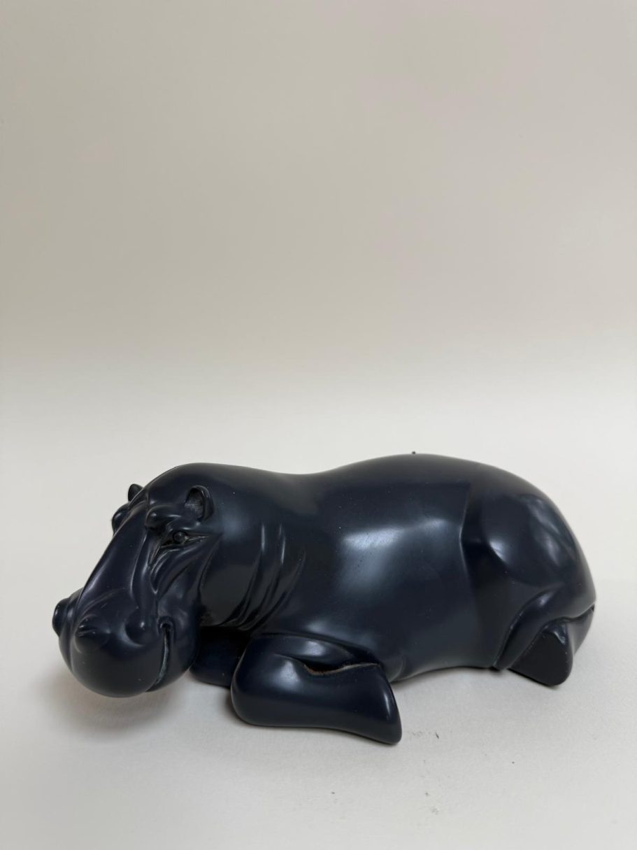 Hippopotame en sculpture noire, couché sur le côté.