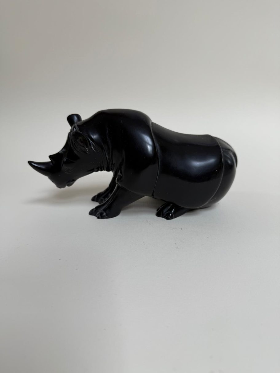 Sculpture d'un rhinocéros en résine noire sur fond clair.